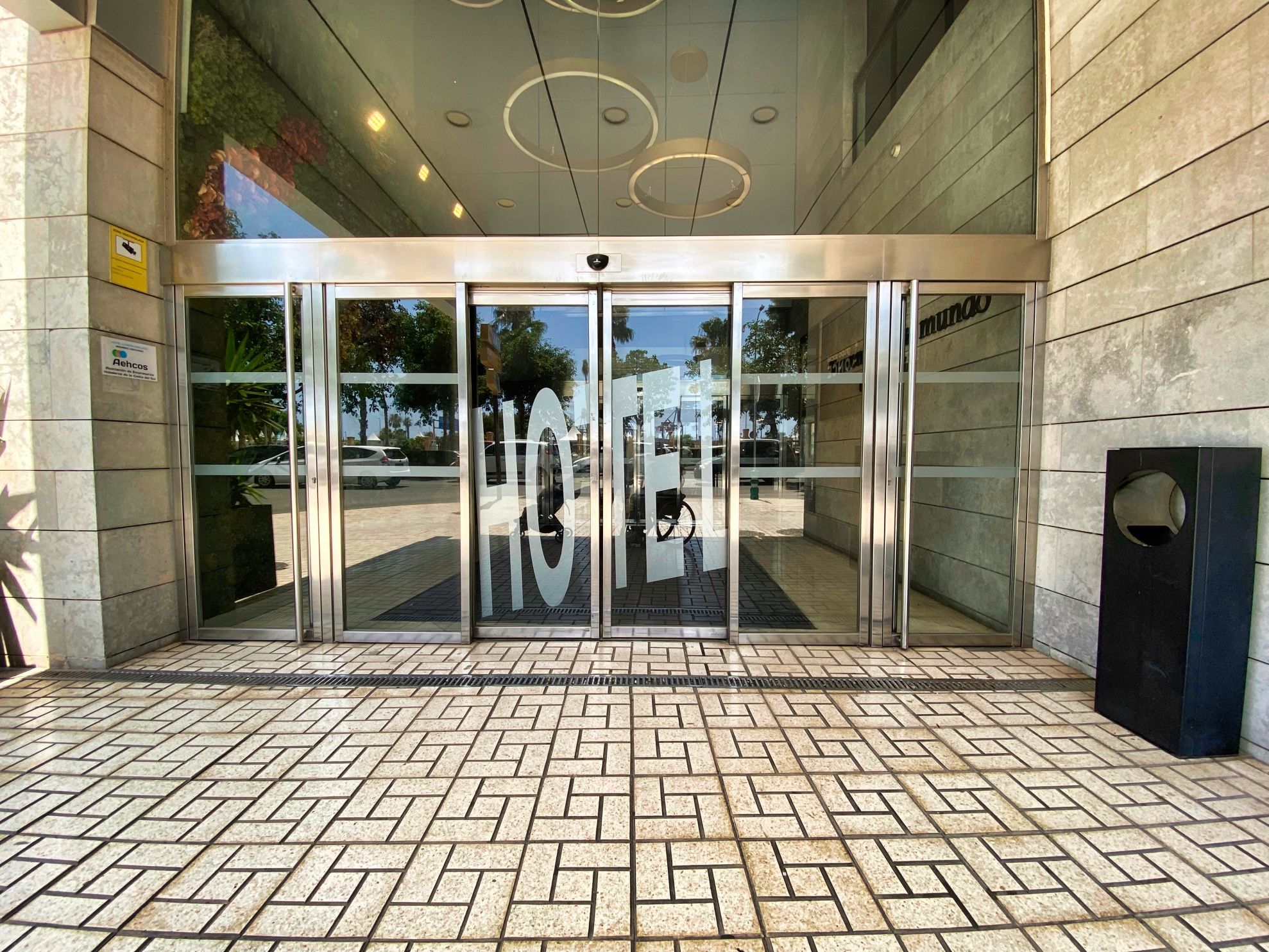 Hotel entrance, photo taken from the outside. Two sliding doors with "hotel" written in huge letters across them.