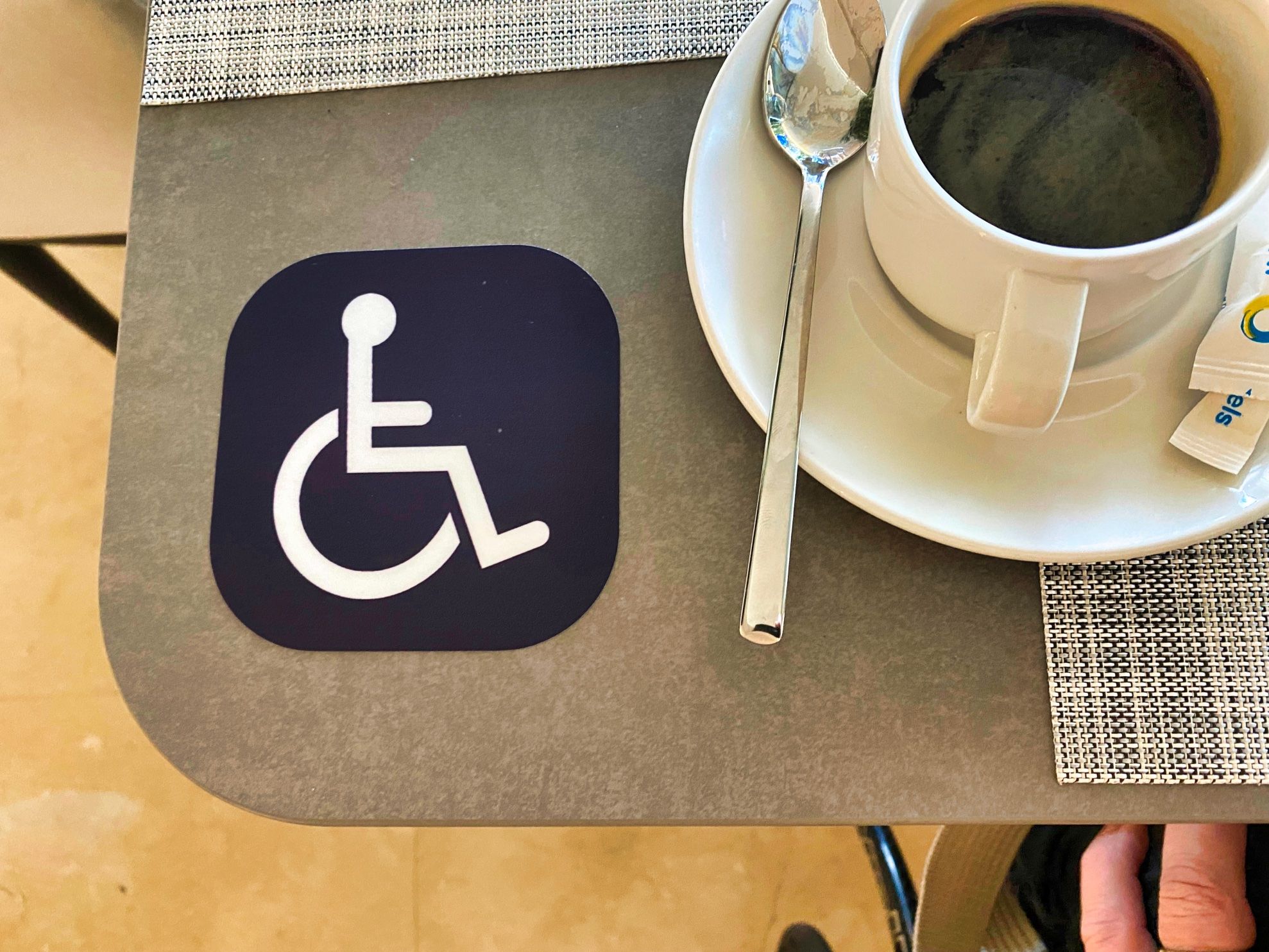 Table with a cup of coffee and on the table a sign with a person in a wheelchair.